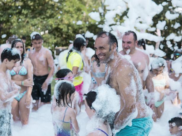 Festa di schiuma all'aperto con adulti e bambini che si divertono.