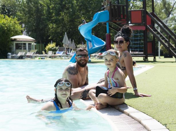 Famiglia felice in piscina con scivolo blu.