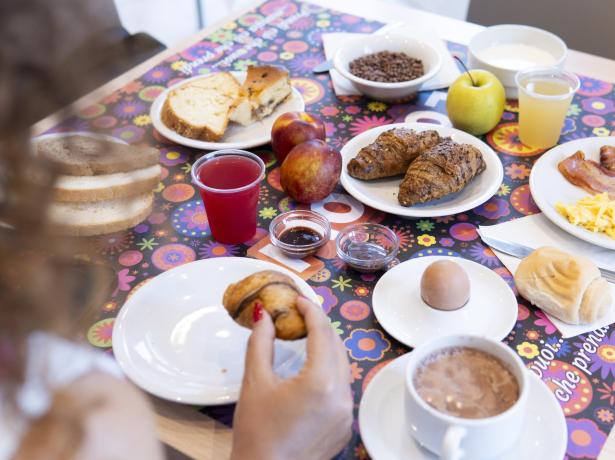 Colazione ricca con croissant, uova, frutta e bevande.