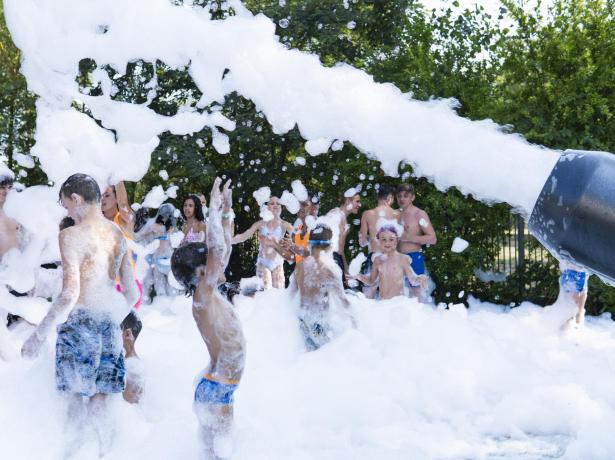 Persone si divertono in una festa di schiuma all'aperto.