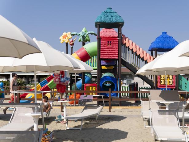 Spiaggia con parco giochi colorato e ombrelloni bianchi.