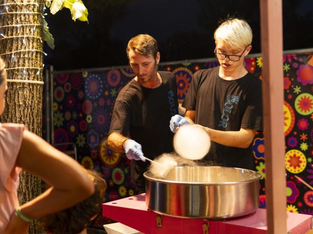 Zwei Personen machen Zuckerwatte auf einer bunten Party.